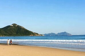 A beach with a mountain in the background, clear skies, and calm water. - Miss You Guesthouse (Shenzhen)