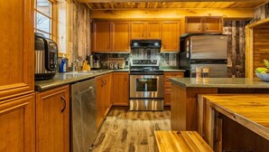 A kitchen with wooden cabinets, stainless steel appliances, and a wooden floor. - The Escapade - Private hot tub with pool table 6BR (Sainte-Lucie-des-Laurentides)
