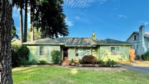 Una casa de un piso con porche delantero, chimenea y césped bien cuidado.