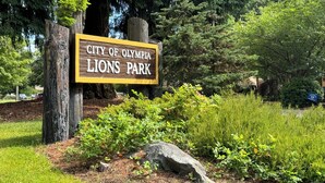 Un letrero del Parque Lions City of Olympia, con un poste de madera y un borde amarillo.