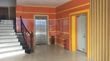 A hotel lobby with a staircase, elevators, and a reception area.