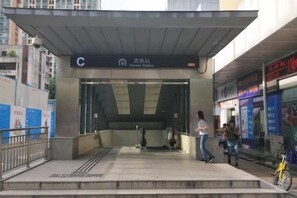 A subway station entrance with a canopy, a sign indicating the station name, and a pedestrian crossing. - Seven Orange Hotel (Shenzhen Yannan Metro Station Huaqiang North Branch) (Shenzhen)