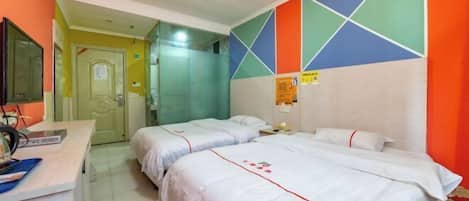 Quarto de hotel com duas camas, uma escrivaninha com computador e banheiro com espelho.