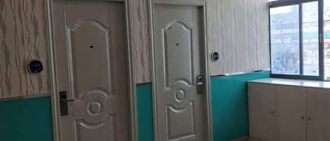 A room with two doors, a window, and a light-colored floor.