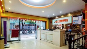 A hotel reception area with a modern design, featuring a reception desk, a digital screen displaying the hotel name, and a staircase leading to the upper floors. - Seven Orange Hotel (Shenzhen Yannan Metro Station Huaqiang North Branch) (Shenzhen)