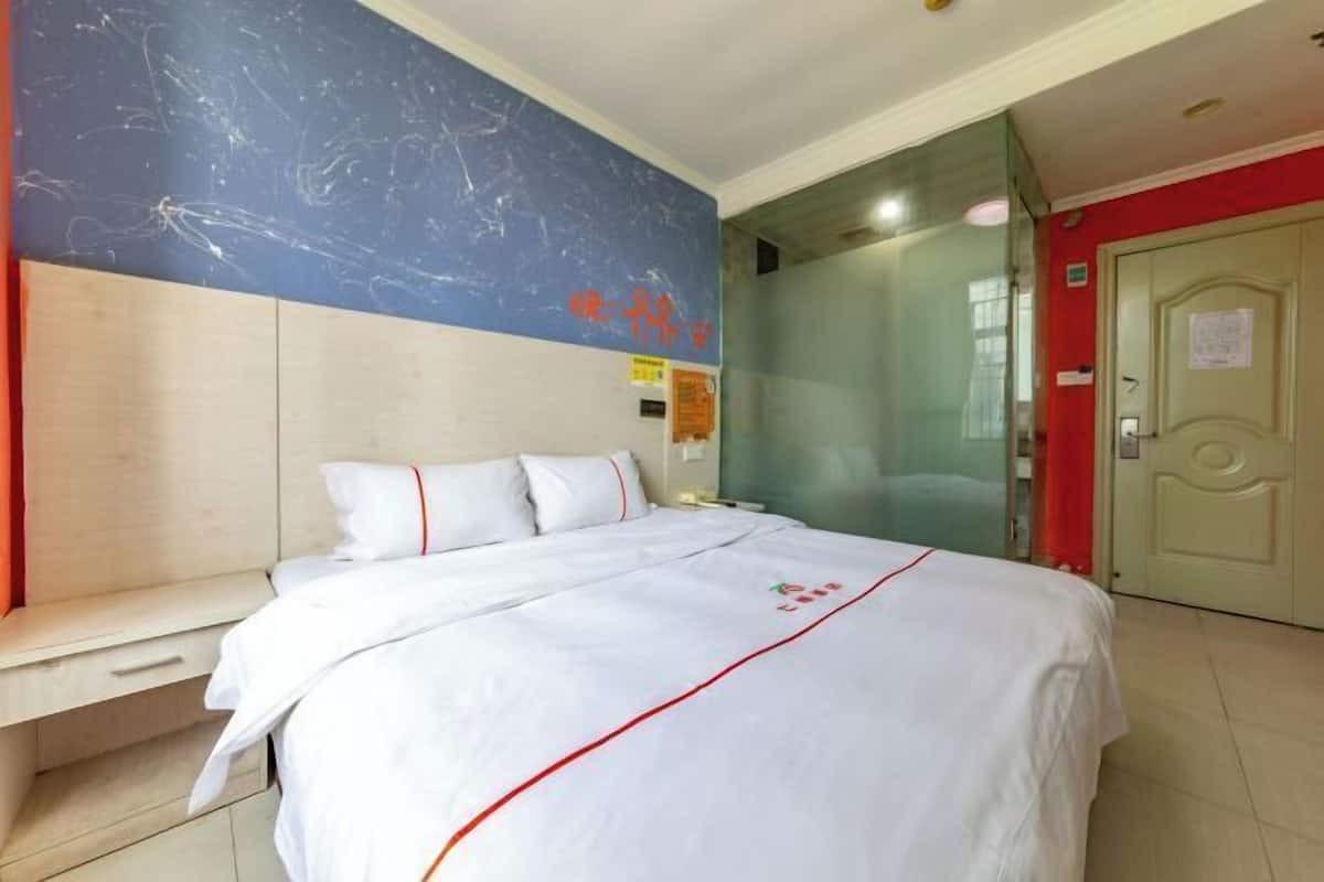A hotel room with a bed, a bedside table, a wall with a blue and white design, and a door.