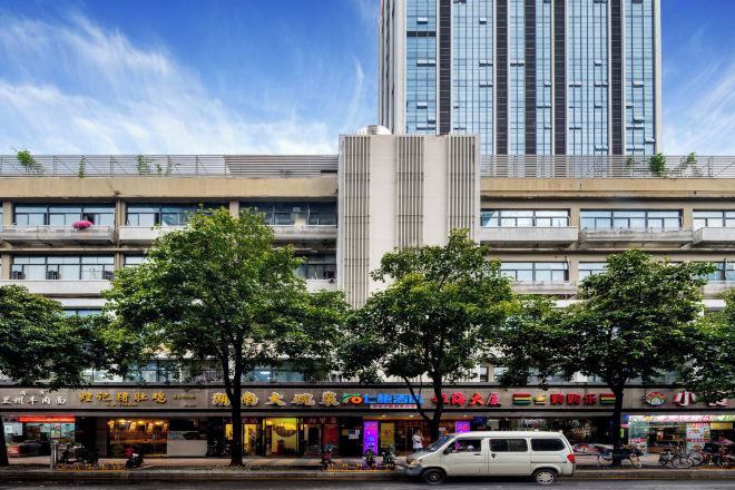 Un edificio de varios pisos con locales comerciales en la planta baja, una estructura vertical central y un cielo despejado.
