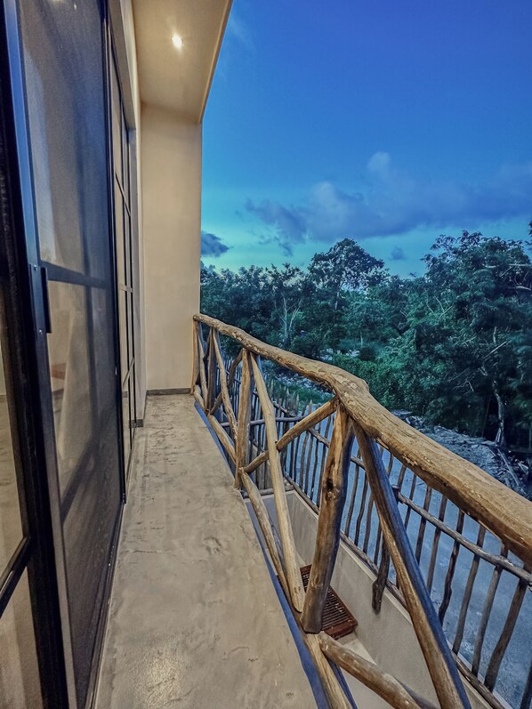 A balcony with a wooden railing overlooking a forested area.