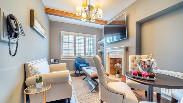 A modern living room with a fireplace, a TV mounted on the wall, and a dining area with a table and chairs. - Lundin Links - UKC6916 (Turnberry)