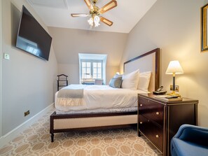 A bedroom with a bed, bedside table, lamp, and a ceiling fan.