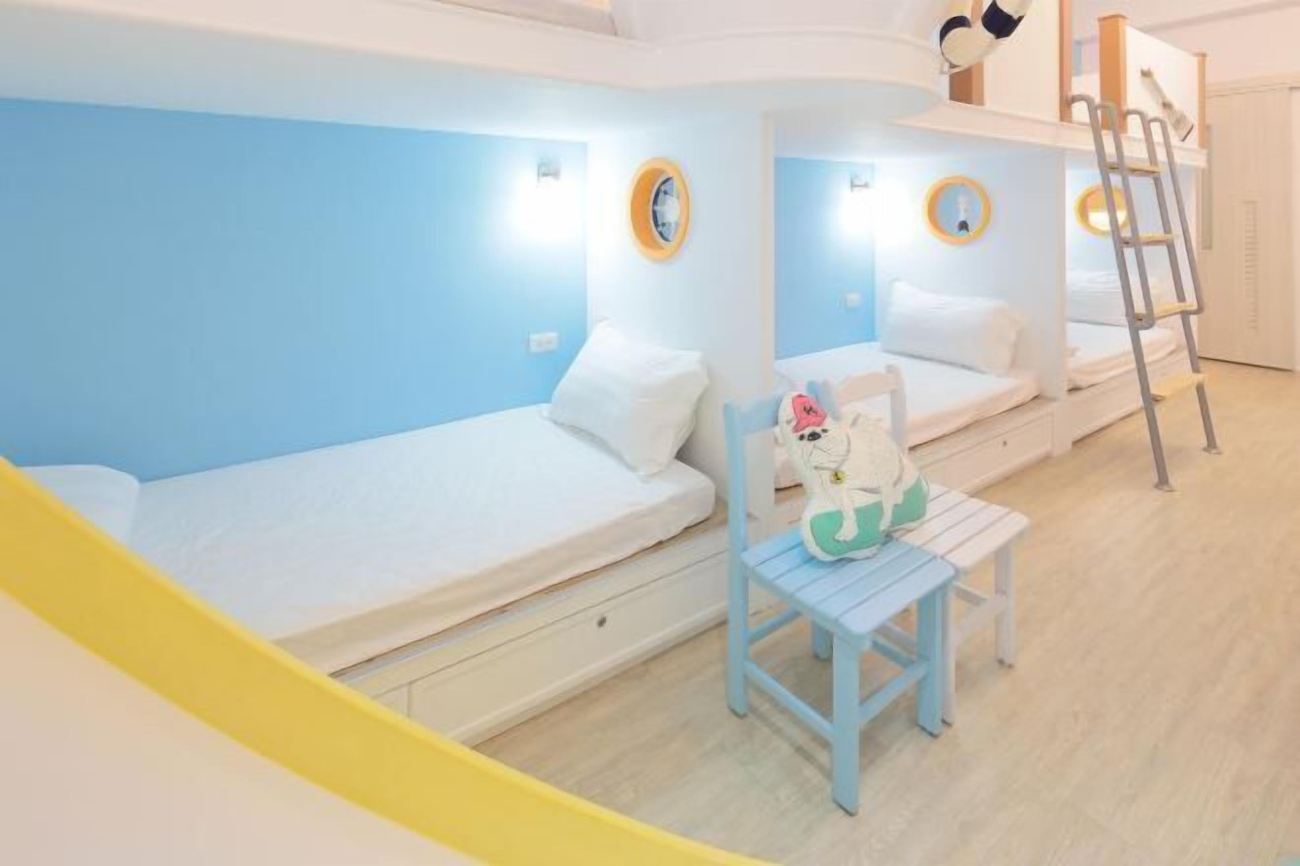 A children's room with bunk beds, a small chair, and a ladder.