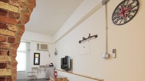 A modern living room with a brick wall, a television, a dartboard, and a small table. - Xigang Waipojia (Tainan)