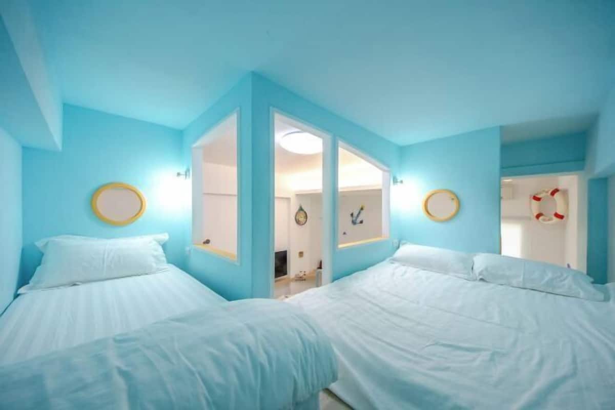 A room with two beds, a mirror, and a door leading to another room.
