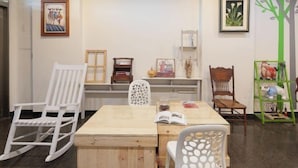 A room with a wooden table, white rocking chairs, and a green shelf with toys. - Xigang Waipojia (Tainan)