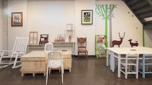 A children's playroom with a wooden table, chairs, a rocking chair, and a green shelf with toys. - Xigang Waipojia (Tainan)