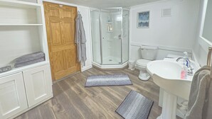 Ein Badezimmer mit Dusche, Toilette, Waschbecken und Ablagekörben.