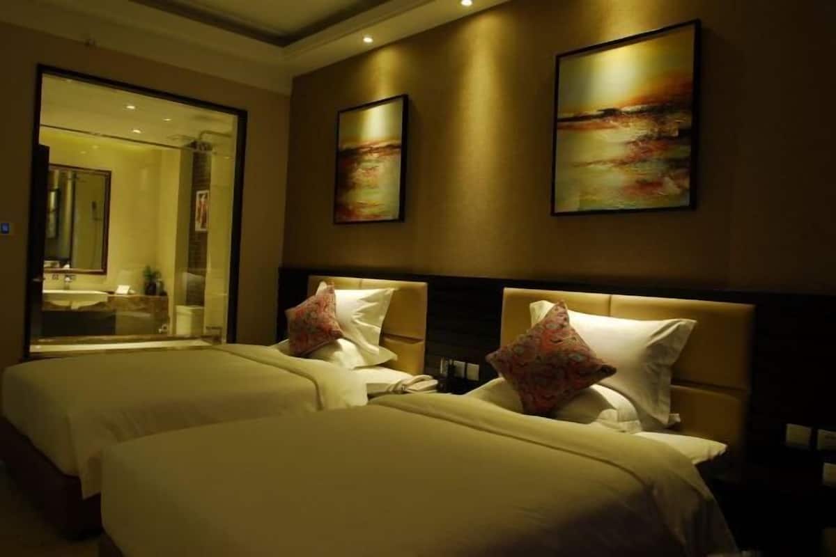 A hotel room with two beds, a large mirror, and artwork on the walls.