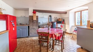 A kitchen with a red refrigerator, grey cabinets, a wooden dining table with chairs, and a stone pillar.