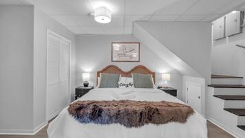Une chambre à coucher bien aménagée, avec un grand lit, deux tables de chevet, une tête de lit et un escalier.