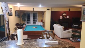 A living room with a pool table, a fireplace, and a television. - Charming 1-bedroom house in wonderful Severn with office,   WiFi, fitness room (Severn)