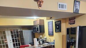 A kitchen with a central island, bar stools, a refrigerator, and various kitchen appliances. - Charming 1-bedroom house in wonderful Severn with office,   WiFi, fitness room (Severn)