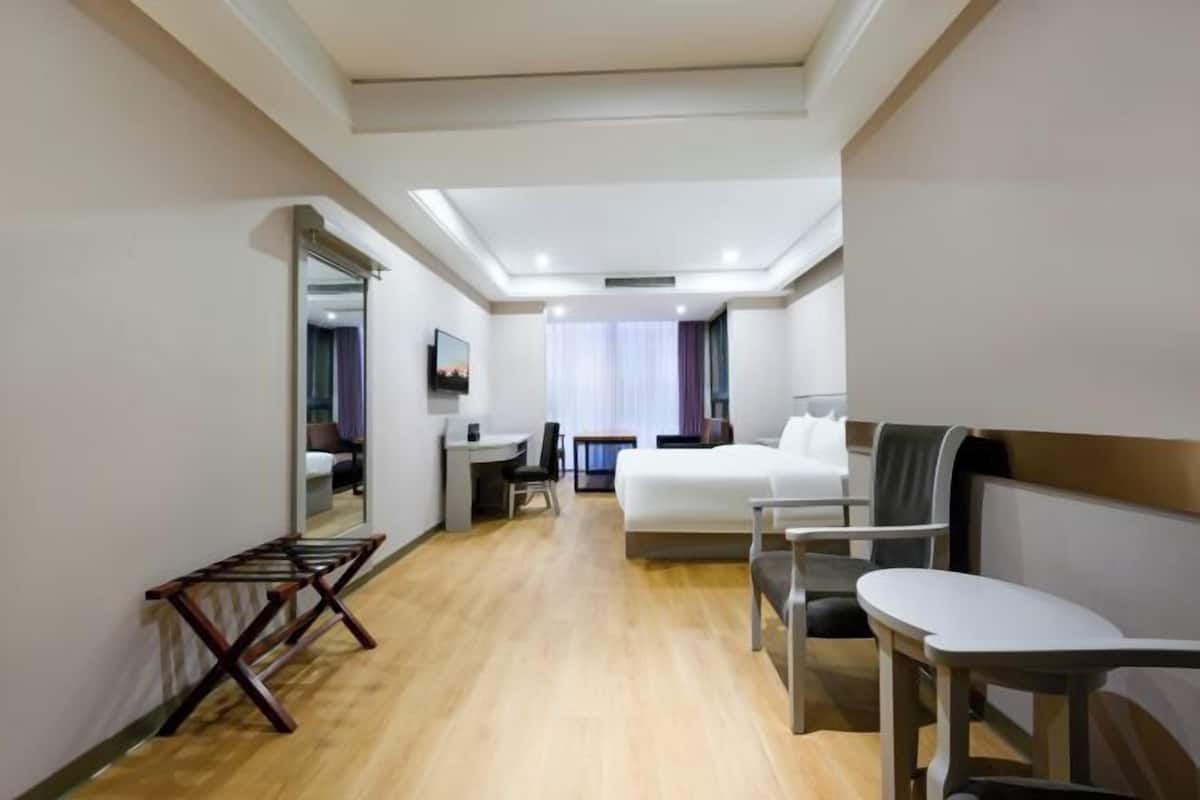 Een hotelkamer met een bed, een bureau, een stoel en een klein tafeltje.