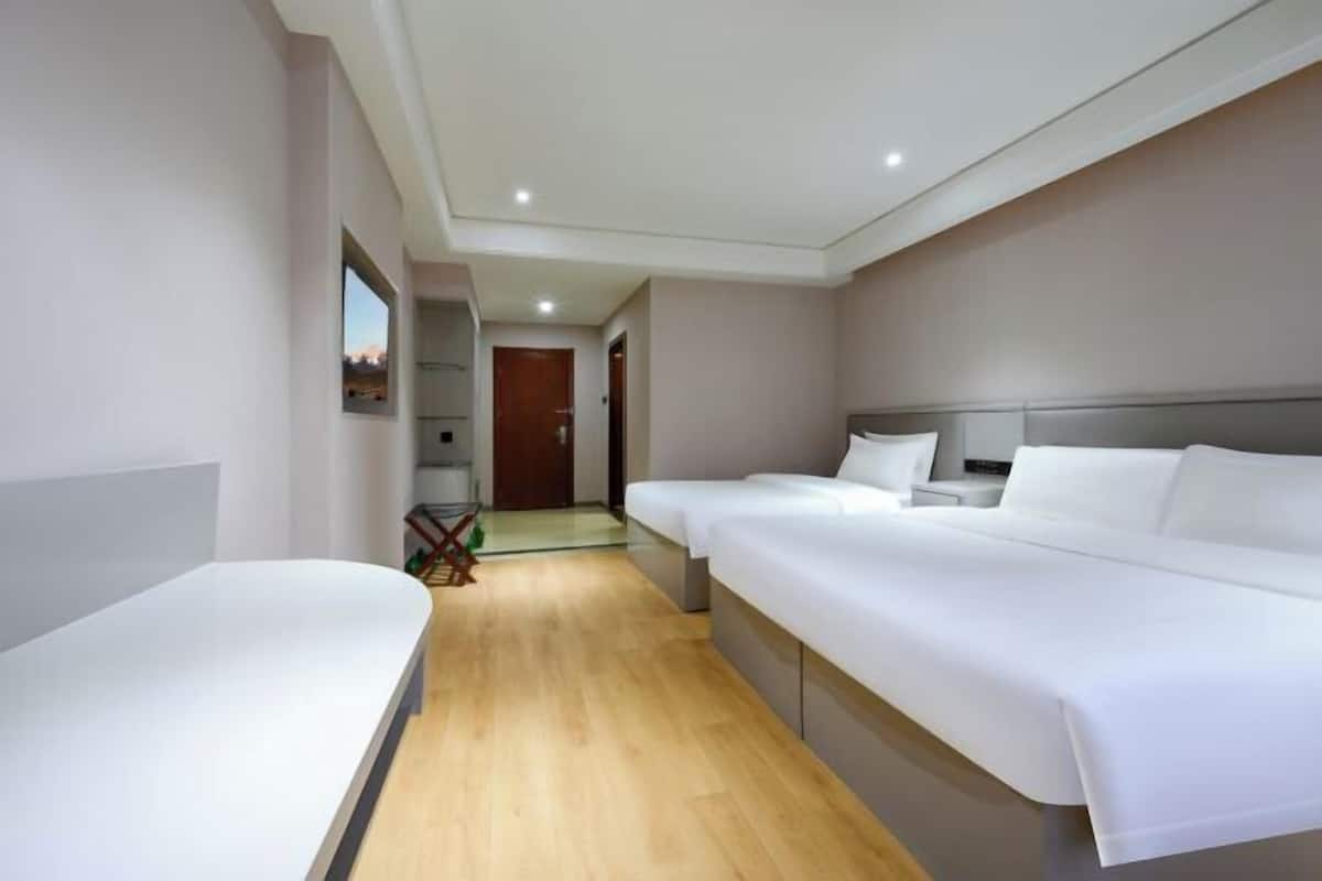 Een hotelkamer met twee enkele bedden, een tafeltje en uitzicht op de gang.