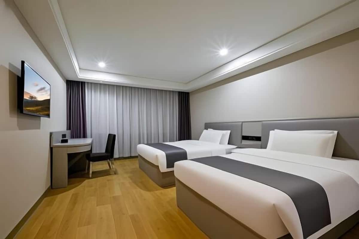 Een hotelkamer met twee bedden, een bureau en een stoel.