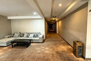 A hotel lobby with a sofa, a coffee table, and a patterned carpet. - YIJING International Hotel (Fuyang)