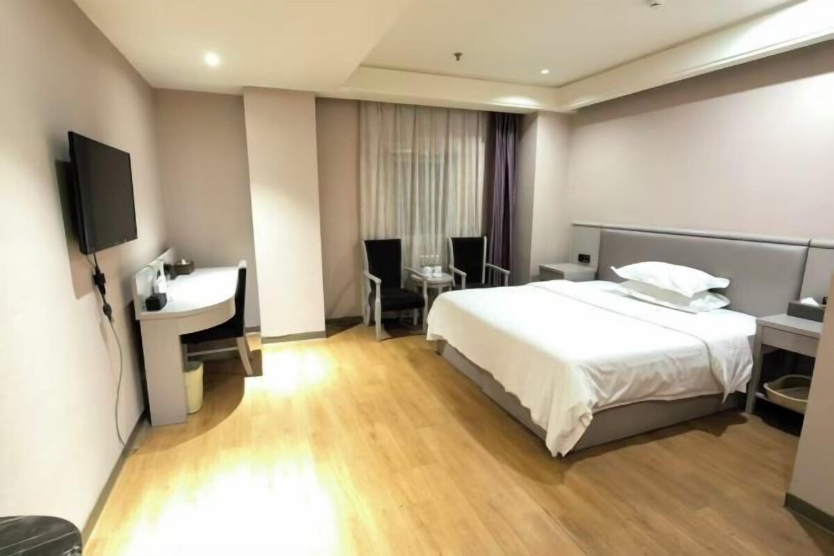 Une chambre d’hôtel comprenant un lit, un bureau avec une chaise, une télévision et une table de chevet.