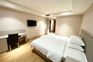 Una habitación de hotel moderna con cama, escritorio y televisor.