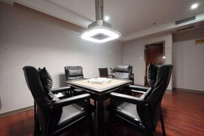 Une salle de conférence avec une table rectangulaire, six chaises en cuir noir et un luminaire au plafond.