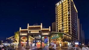 A modern hotel with a traditional archway entrance, illuminated signage, and a well-lit facade. - Yijing International Hotel (Fuyang)