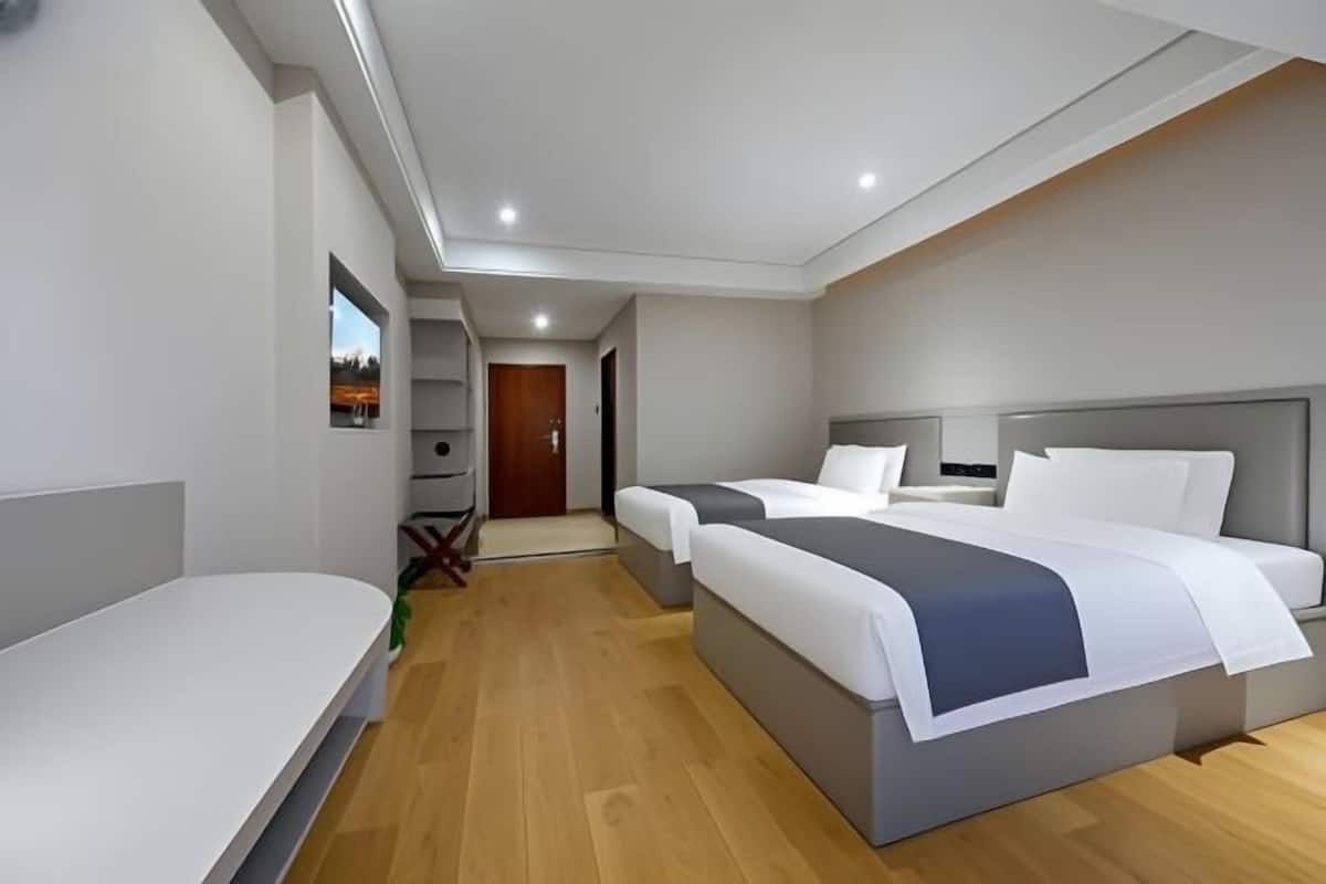 Een moderne hotelkamer met twee bedden, een klein bureau en uitzicht op de omgeving.