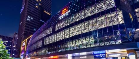 Un edificio moderno con fachada de vidrio y varios niveles, rodeado de otros edificios de gran altura.