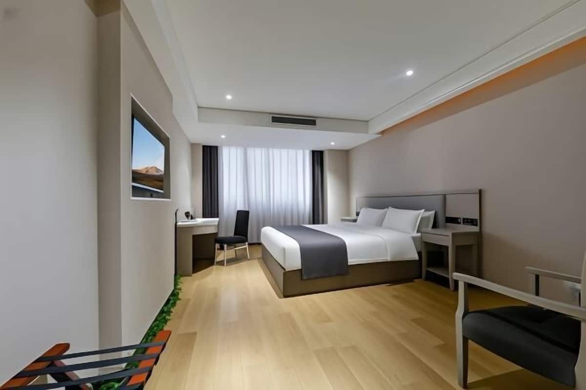 Een moderne hotelkamer met een bed, nachtkastjes, een bureau en een stoel.