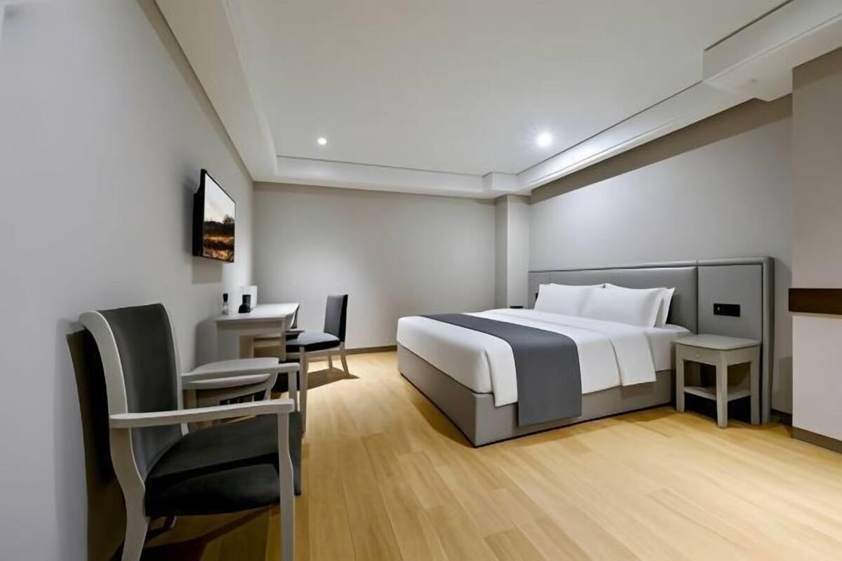 Een moderne hotelkamer met een bed, een bureau, een stoel en een kleine tafel.