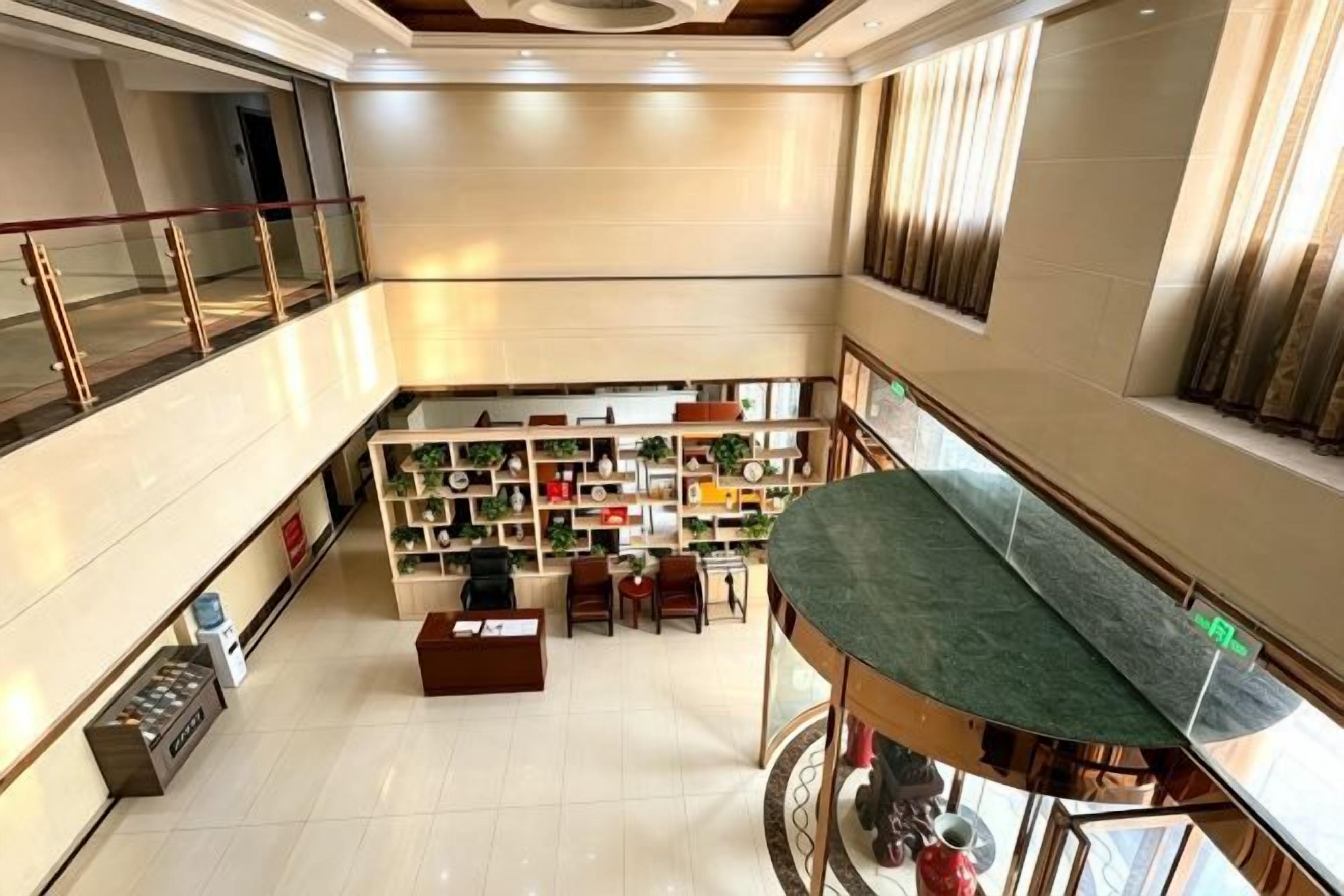 A hotel lobby with a central seating area, a staircase, and a view of the upper floor.