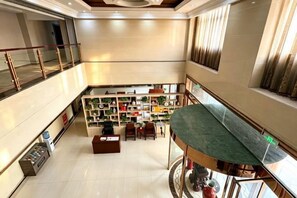 A hotel lobby with a central seating area, a staircase, and a view of the upper floor. - YIJING International Hotel (Fuyang)