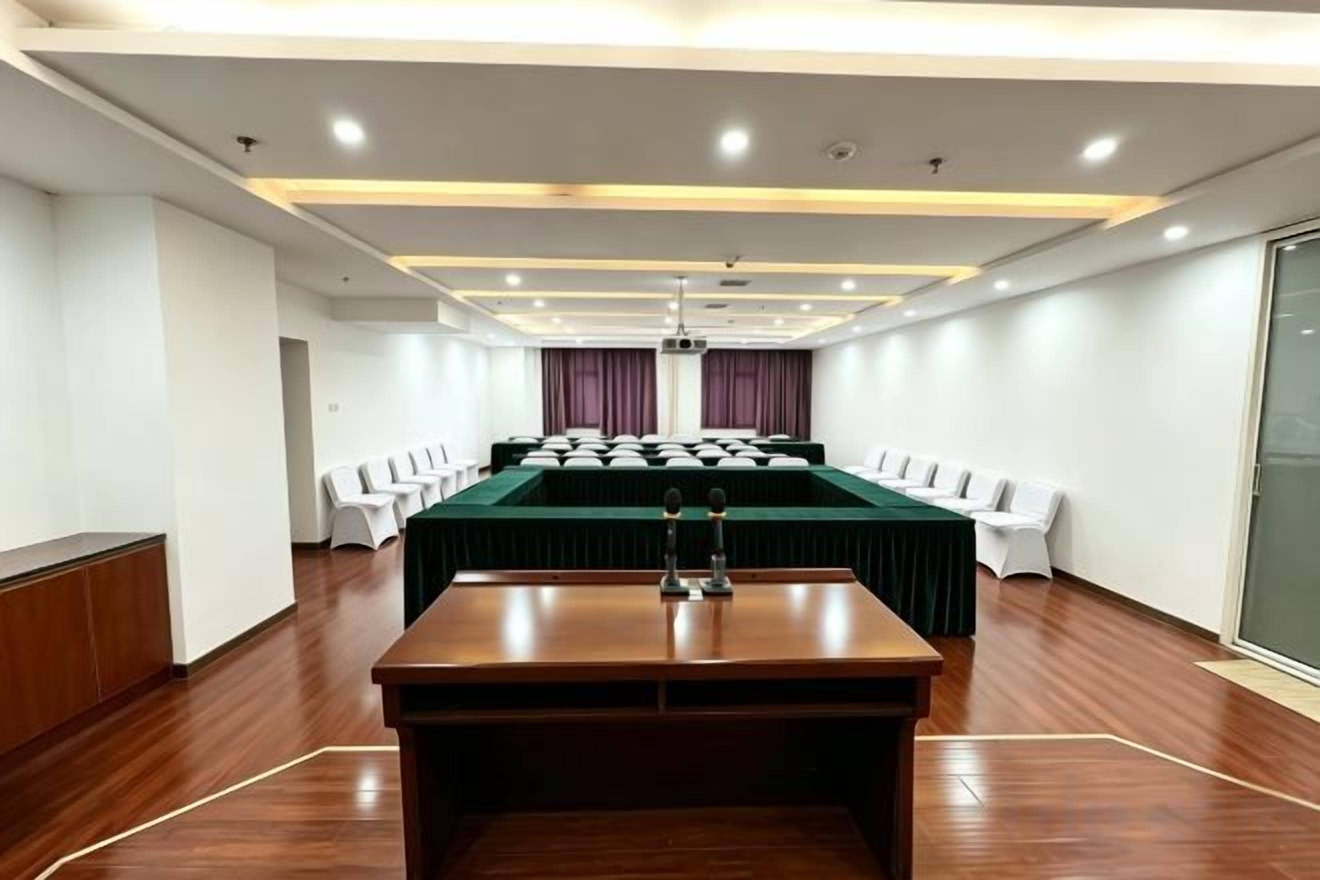 A conference room with a long table, chairs, and a projector screen.