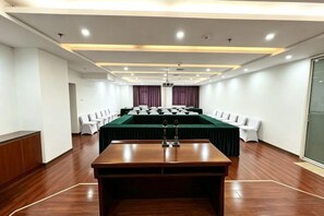 Un salón de conferencias con una larga mesa, sillas y una pantalla de proyector.