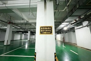A parking garage with white pillars, green flooring, and a sign indicating a reserved parking area. - YIJING International Hotel (Fuyang)