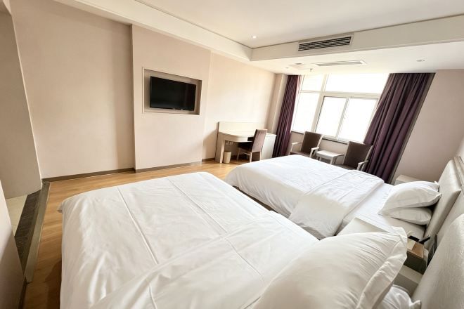 Habitación de hotel con dos camas, un escritorio y un televisor.