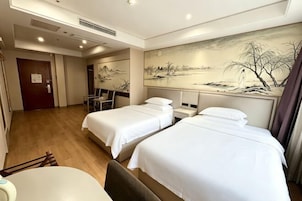 A hotel room with two beds, a desk, a chair, and a painting on the wall.