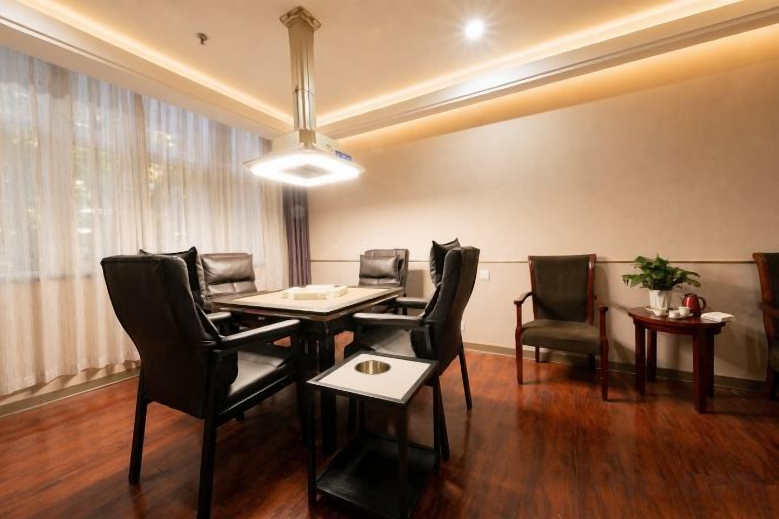 A dining area with a table and chairs, a pendant light, and a small table with a plant.