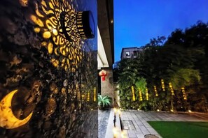 A pathway leading to a building with a decorative wall and string lights. - YIJING International Hotel (Fuyang)