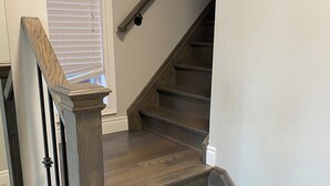 A wooden staircase with a handrail and a dark finish.