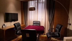 Habitación de hotel con una cama grande, un escritorio con televisor de pantalla plana, dos sillas y una lámpara de pie.