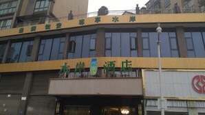 Un hotel con fachada amarilla y grandes ventanales.