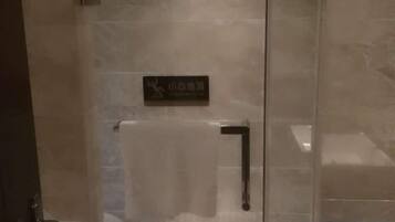 A glass door with a sign, a towel rack, and a shower area.